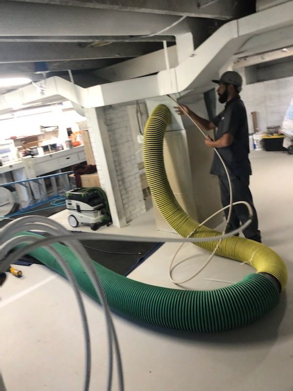 Man handling large industrial ventilation hoses.