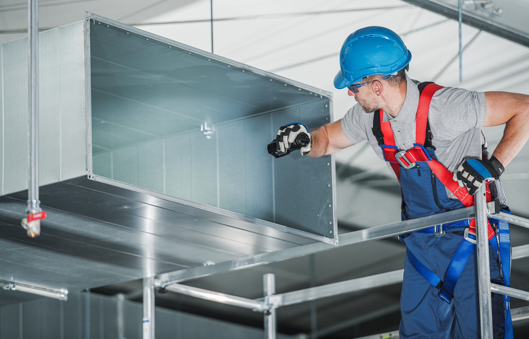 Worker inspecting industrial air duct system.